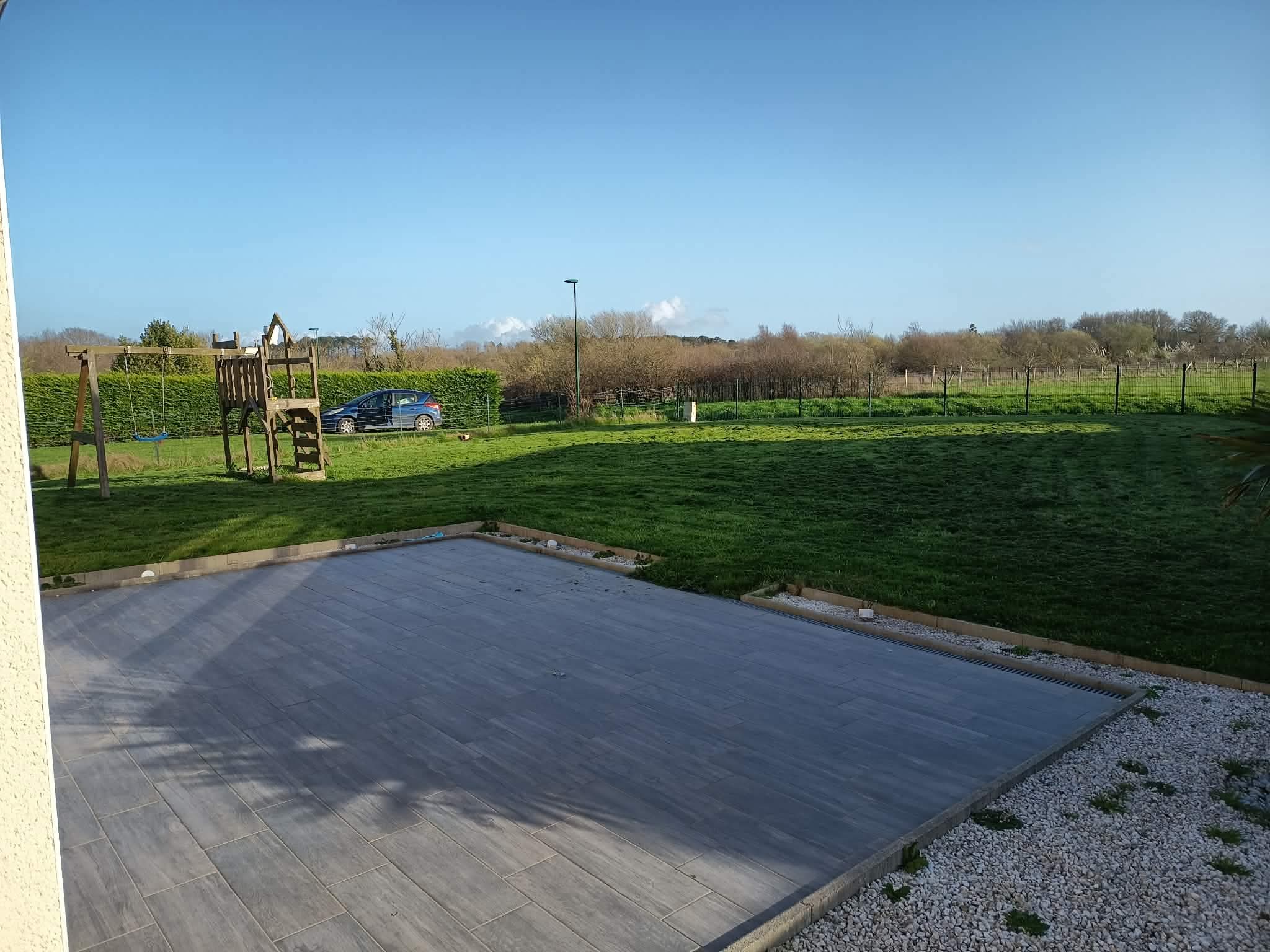 Grande terrasse carrelée et jardin avec aire de jeux
